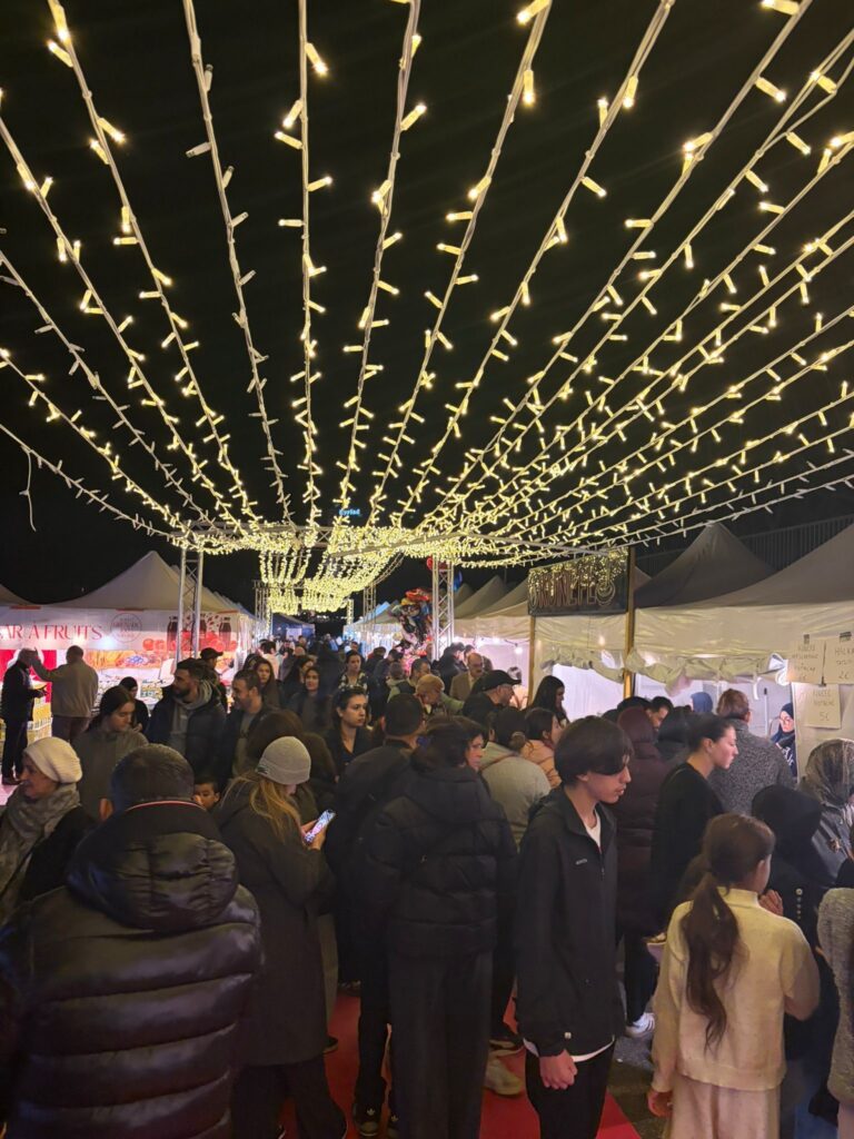 Guirlandes lumineuses décoratives Revolt Location déployées en éventail au-dessus d'une allée de marché nocturne animée, bordée de stands.