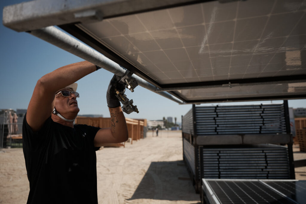 Technicien fixant un panneau photovoltaïque sur une structure aluminium lors du montage d'une installation solaire sur site événementiel.