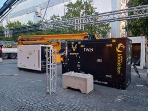 Groupe électrogène Stage V Twin Revolt Location installé sur un montage scénique urbain, avec nacelle élévatrice et structure de trusses en arrière-plan.