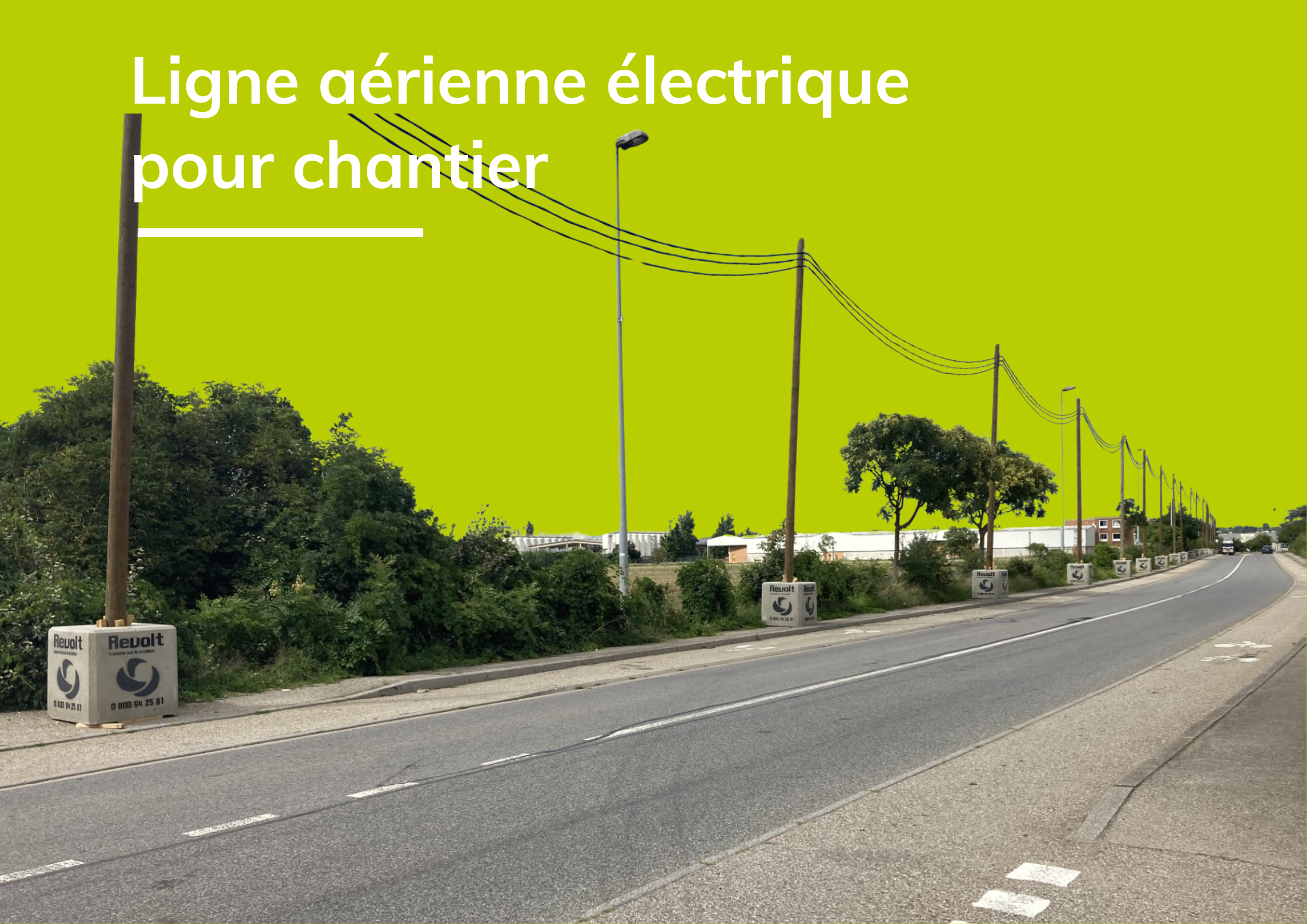 Ligne aérienne électrique pour chantier Revolt Location, poteaux et plots béton flanqués le long d'une route bordant une zone d'activité.