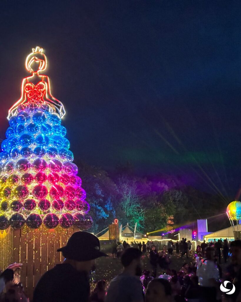 Décoration lumineuse en forme de sapin installée sur un site événementiel nocturne