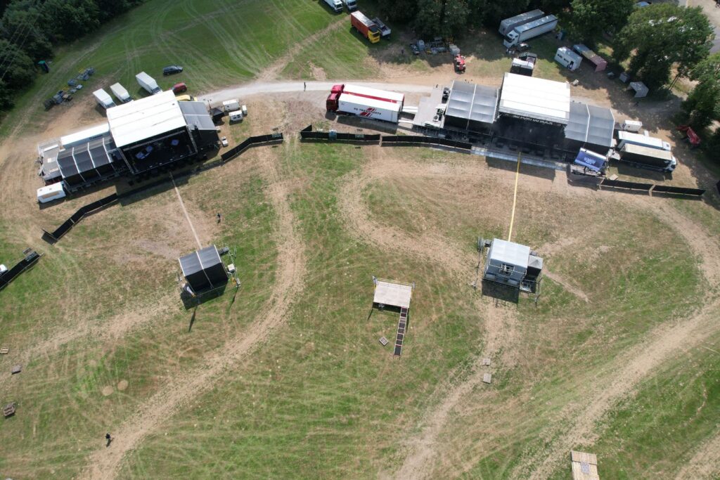 Vue aérienne d’un site événementiel en plein air avec scènes, structures temporaires et installations techniques