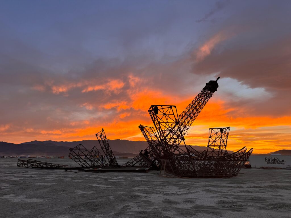 Structure artistique monumentale installée dans le désert au coucher du soleil