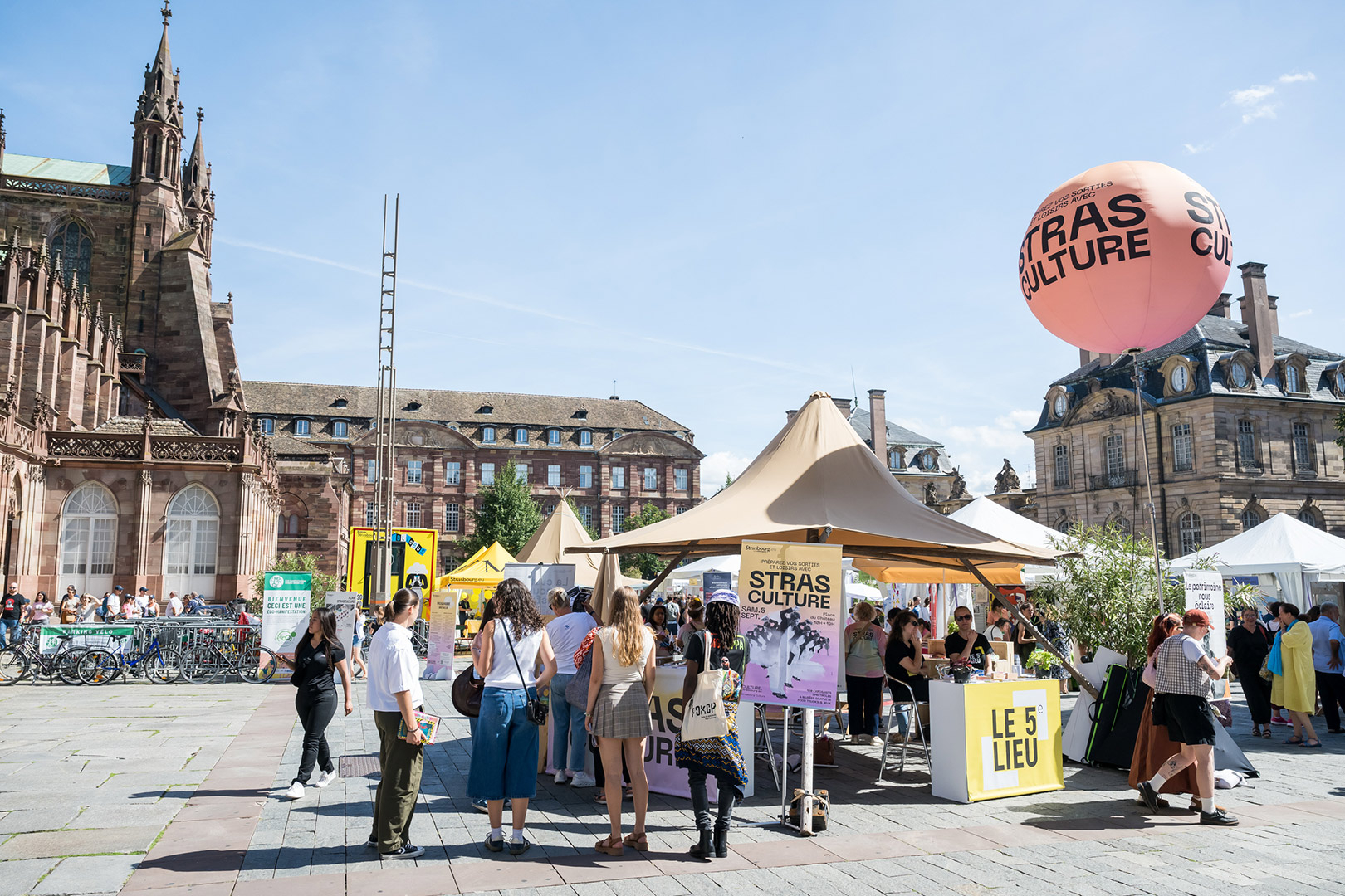 Événement culturel en plein air sur une place de Strasbourg, avec des stands et tentes devant des bâtiments historiques